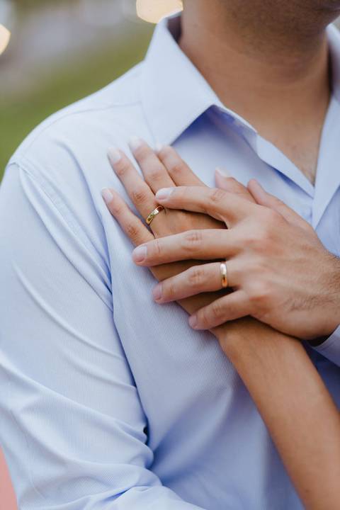 Detalhe das maos entrelacadas dos noivos mostrando as aliancas de casamento'
