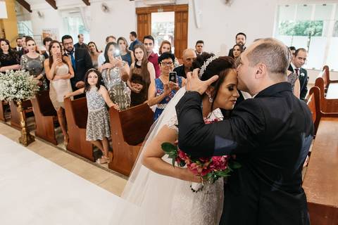Foto do noivo dando um beijo na testa da noiva na hora da entrada da noiva'