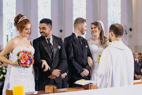 Casamento duplo, de gêmeas, noivos no altar da igreja se olhando'