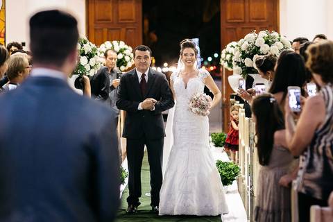 noiva entrando na igreja com noivo olhando para ela'