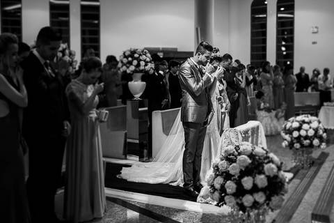 cerimônia de casamento, noivos no altar fazendo o sinal da cruz'