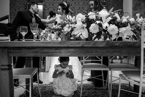 criança brincando em baixo da mesa com noiva ao fundo'