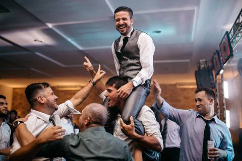 noivo sendo carregado nas costas por convidados durante a festa de casamento'