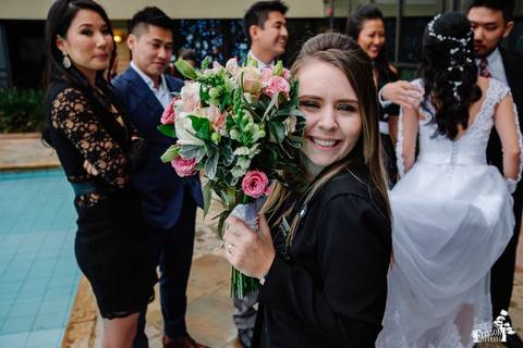 Fotografia de Casamento Boho no Moress Fazenda, Londrina, de fotógrafo de casais de Maringá/PR, em dia nublado e com chuva, foto da assessora sorrindo e segurando o bouquet'