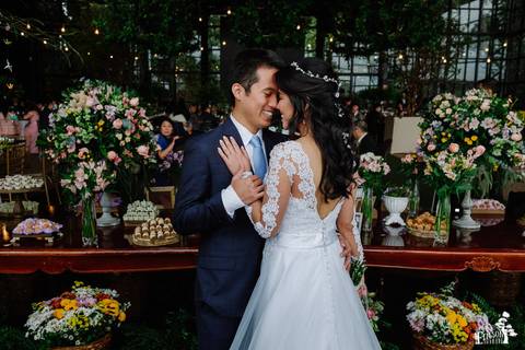 Fotografia de Casamento Boho no Moress Fazenda, Londrina, de fotógrafo de casais de Maringá/PR, em dia nublado e com chuva, foto dos noivos na frente da mesa de doces depois da cerimônia'