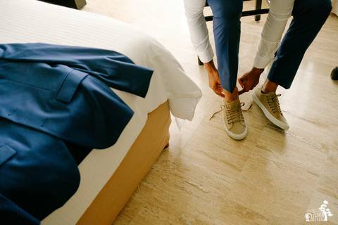 Fotografia de casamento na praia, casamento pé na areia, fotógrafo de Maringá/PR fotografando destination wedding em Cancun, Mexico, foto do making of do noivo se vestindo para o casamento, colocando os sapatos'