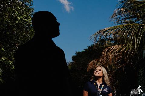 foto em ensaio pré-wedding, noivo em silhueta e noiva atrás sorrindo'