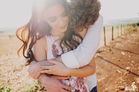foto emocionante de casal em ensaio pré casamento, pré-wedding, no campo, noivo abraçando a noiva com muito carinho'