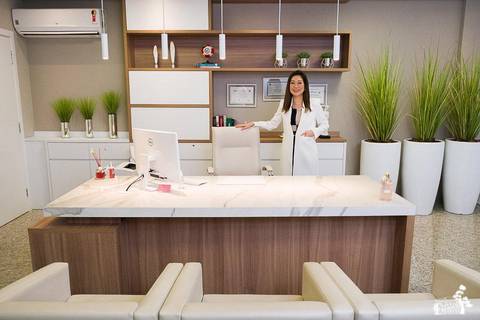 Retrato empresarial ou corporativo, foto do ambiente de trabalho dentro da empresa, com proprietária de pé segurando uma cadeira branca'