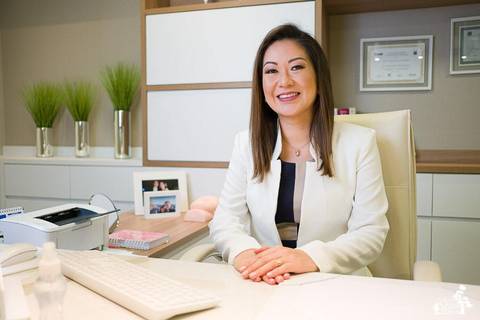 retrato empresarial de oftalmologista, sentada em cadeira branca, olhando para a câmera'