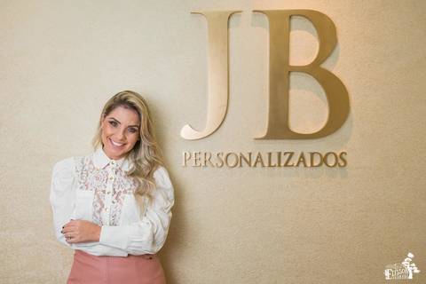 Retrato empresarial na empresa da empresária empreendedora Jhuliany, JB Robes Personalizados, empresaria posando ao lado do letreiro com a logomarca da empresa'