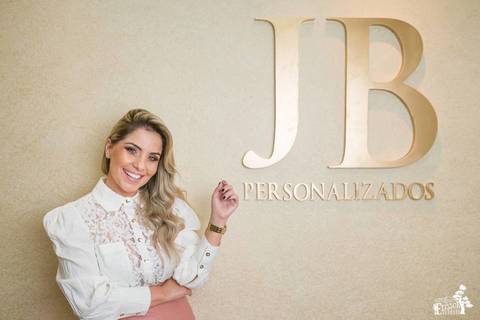 Retrato empresarial na empresa da empresária empreendedora Jhuliany, JB Robes Personalizados, empresaria posando ao lado do letreiro com a logomarca da empresa sorrindo verdadeiramente'