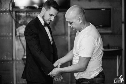 padrinho conferindo se o terno está arrumado, na barbearia, enquanto o noivo se arruma para o casamento'