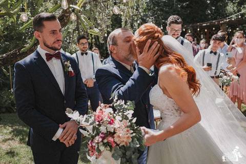 pai beijando a testa da noiva enquanto noivo espera'