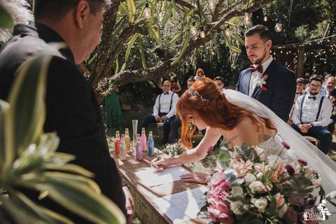 Noiva assinando o documento de casamento durante cerimônia civil de casamento, ao ar livre, no estilo boho chic'