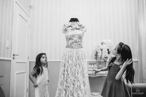 Fotografia de casamento, antes do casamento, com as milhas da noiva brincando com o vestido de noiva durante o making off da noiva, no salao de beleza'