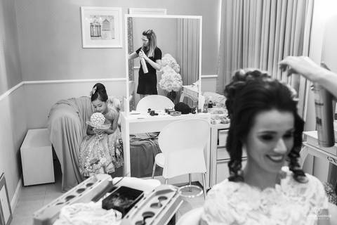 Fotografia de casamento, antes do casamento, com a filha da noiva admirando o bouquet que ela irá entrar na igreja'