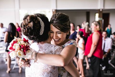 Festa de casamento durante o dia, cunhada pegou o bouquet e está abraçando a noiva'