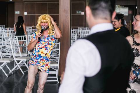 Festa de casamento durante o dia, convidado vestido de mulher cantando durante a festa'
