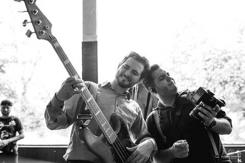 Festa de casamento durante o dia, convidado tocando baixo e fotógrafo tocando guitarra imaginária'