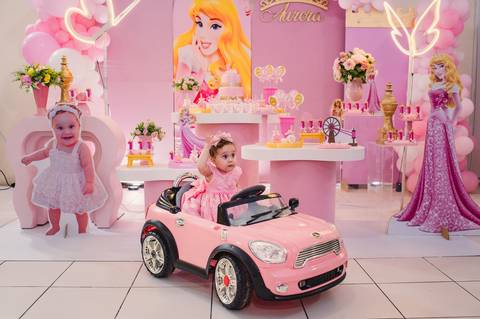 Festa de aniversário infantil - fotógrafa Claudia Wallauer - aniversariante no seu carro de brinquedo cor de rosa em frente à decoração de princesa'