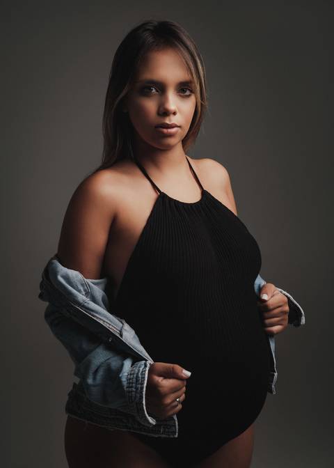Gestante de body preto e jaqueta jeans'