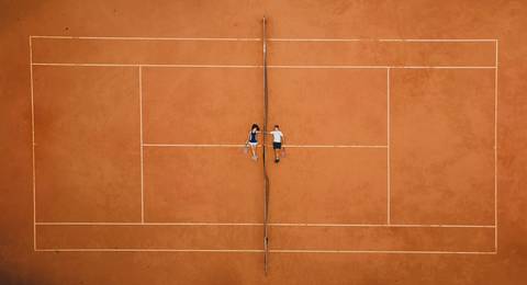 Foto de casal na quadra de tenis de saibro'