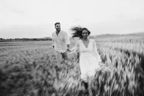 casal correndo no campo de trigo'