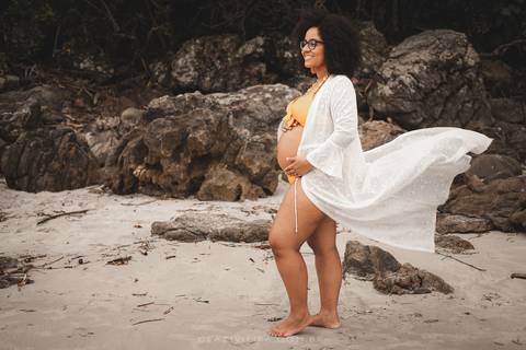 gestante com vestido voando na praia'