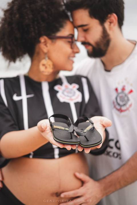 gestante segurando havaianas junto com pai na praia'