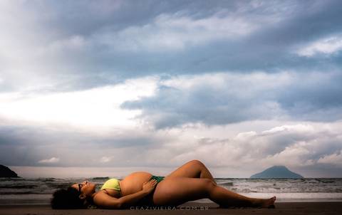 gestante deitada na praia com o céu'