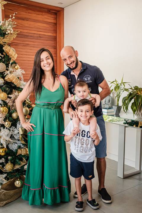 família posando para foto ao lado da árvore de natal'