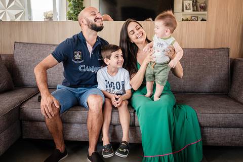 pai mãe e filhos brincando no sofá'