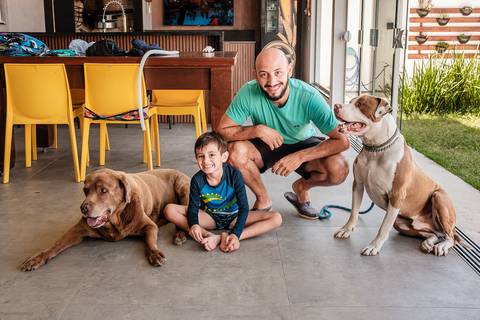 pai sentado com filho mais velho e os cachorros da família'