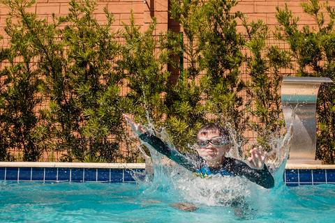 criança pulando na piscina'