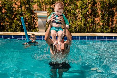 pai brincando com os filhos na piscina'