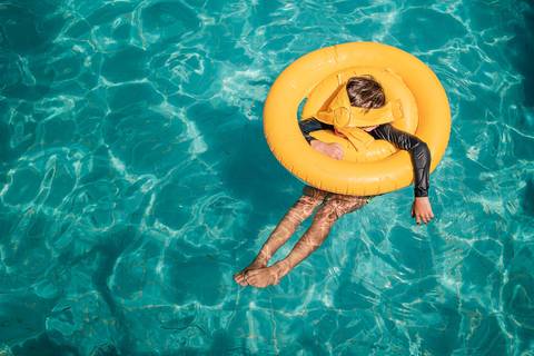 criança brincando com bóia na piscina'