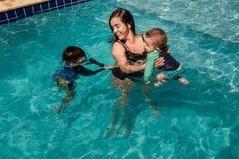 mãe com os filhos na piscina'