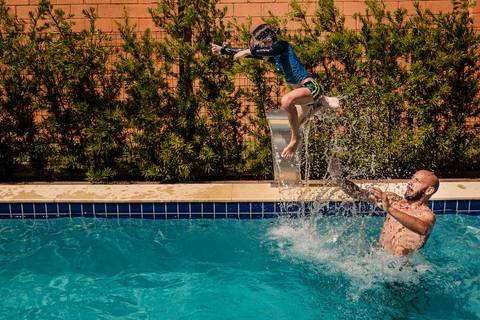 pai jogando filho na piscina'