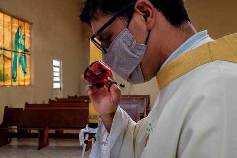 padre paga o oleo do batismo no vidro'