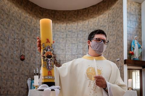 padre e vela do batismo'