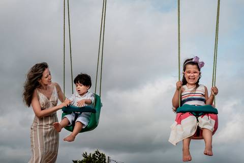 mãe brincando com as crianças no balanço'