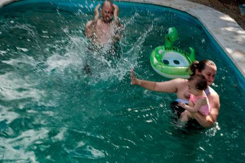 criança pulando na água da piscina'