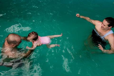 pai mãe e filha na piscina'