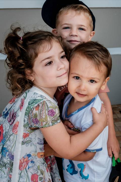 três crianças se abraçando'