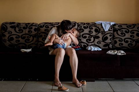 mãe abraçando o filho no sofá da sala'