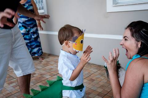 mãe brinca com o filho usando máscara de dinossauro'