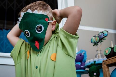 criança usando máscara infantil de dinossauro'