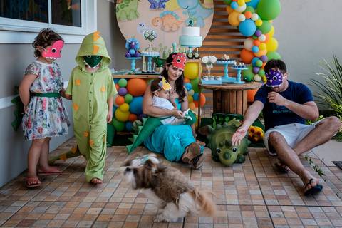 pais, filho, primos e cachorra sentados na frente da mesa do bolo'
