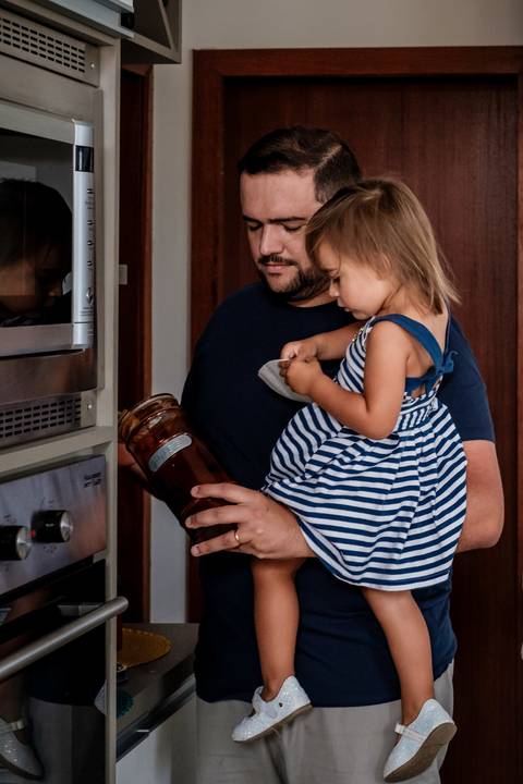 pai com a filha no colo fazendo café'